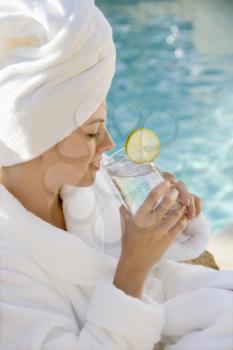 Royalty Free Photo of a Woman Wearing a Robe Drinking Next to a Pool