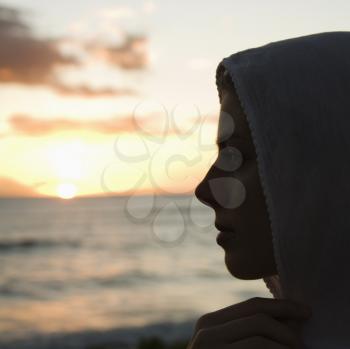 Royalty Free Photo of a Woman With a Scarf Over Her Head Watching the Sunset Over Ocean