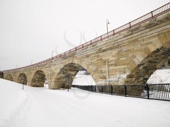 Royalty Free Photo of a Stone Bridge Over a Snow Covered Road