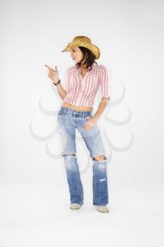 Young adult Caucasian woman wearing cowboy hat pointing finger like a gun.