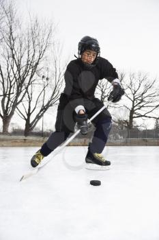 Royalty Free Photo of a Boy in an Ice Hockey Uniform Skating on an Ice Rink Moving a Puck