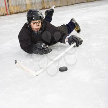 Royalty Free Photo of a Boy in Uniform Sliding on Ice Holding a Stick Out Towards a Puck