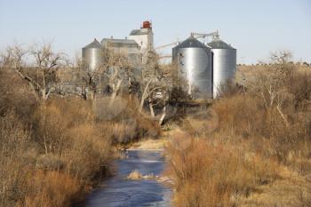 Royalty Free Photo of Storage Silos by a Creek in a Rural Setting