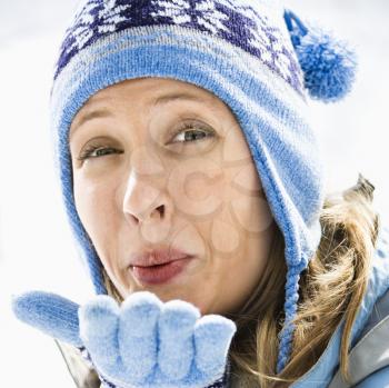 Royalty Free Photo of a Smiling Woman Wearing a Blue Ski Cap and Gloves Blowing a Kiss