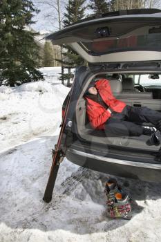 Royalty Free Photo of a Teenager Sleeping in the Back of SUV With Ski Gear