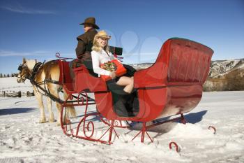 Royalty Free Photo of a Woman Holding a Present in a Horse-Drawn Sleigh