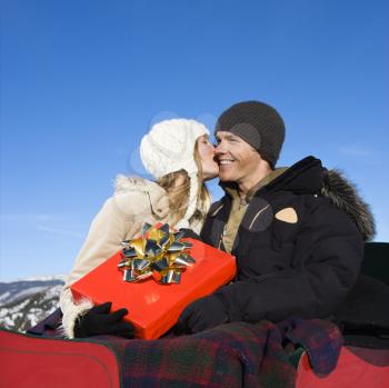 Royalty Free Photo of a Young Woman Kissing the Cheek of a Man in a Sleigh in Winter