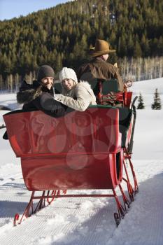 Royalty Free Photo of a Man Driving a Horse Drawn Sleigh With a Young Couple Looking Back