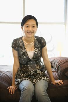 Royalty Free Photo of an Asian Woman Sitting on a Bed