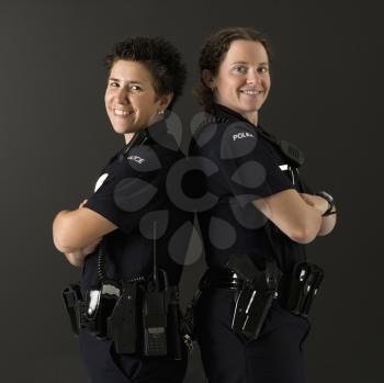 Royalty Free Photo of Policewomen Standing Back to Back With Their Arms Crossed and Smiling
