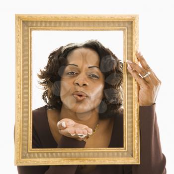 Royalty Free Photo of a Woman Holding a Frame Around Her Head Blowing Out a Kiss