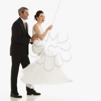 Royalty Free Photo of a Groom Pushing a Bride in Swing Set