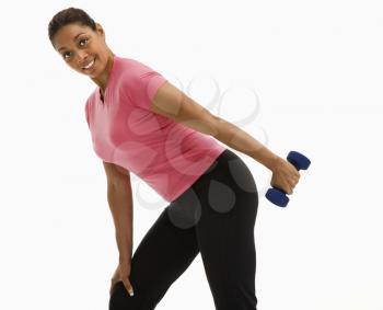 Mid adult multiethnic woman exercising with dumbbell smiling and looking at viewer.