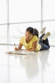 Royalty Free Photo of a Girl Lying on the Floor Doing Homework