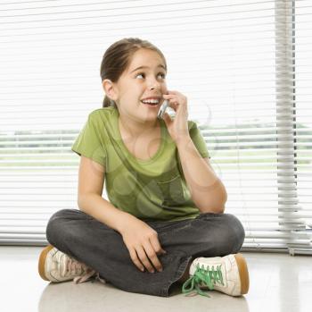 Royalty Free Photo of a Girl Sitting on the Floor Talking on a Cellphone