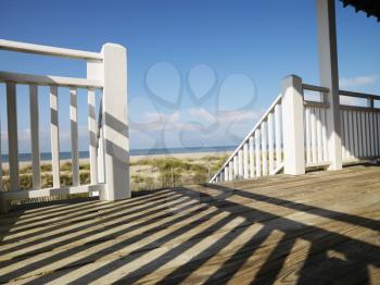Royalty Free Photo of a View of Beach From Porch With Railing Casting Shadow on Wooden Deck at Bald Head Island, North Carolina