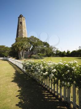 Royalty Free Photo of Bald Head Lighthouse With Fence and Wild Roses at Bald Head Island, North Carolina