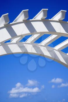Royalty Free Photo of a Low Angle View of Arched White Trellis with Blue Sky