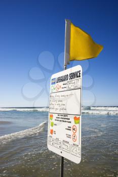 Royalty Free Photo of a Sign and Flag on a Beach in Surfers Paradise, Australia with Lifeguard Schedule