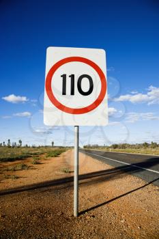 Speed limit kilometer per hour road sign by road in rural Australia.