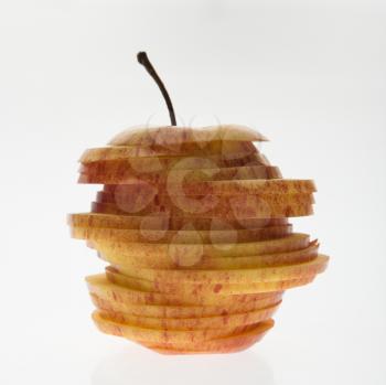 Red apple sliced and stacked against white background.