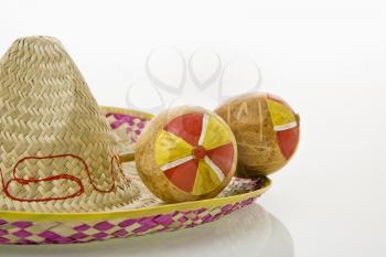 Royalty Free Photo of a Pair of Handmade Mexican Maracas Percussion Musical Instruments on a Sombrero Straw Hat