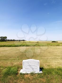 Royalty Free Photo of Cemetery Headstone in a Rural Field Under Blue Sky