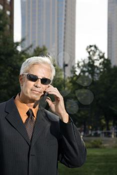 Royalty Free Photo of a Middle-aged Businessman in Sunglasses Holding a Cellphone Outdoors