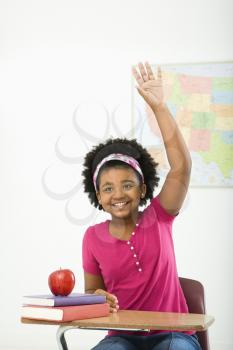 Royalty Free Photo of a Girl Sitting in a Desk Raising Her Hand and Smiling