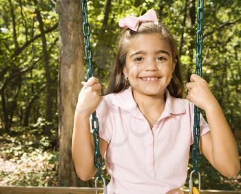 Royalty Free Photo of a Girl Sitting on a Playground Swing Smiling