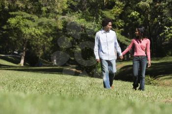 Royalty Free Photo of a Smiling Couple Holding Hands Walking and Talking in a Park