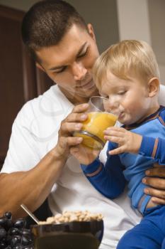 Royalty Free Photo of Father Helping His Toddler Son Drink Juice
