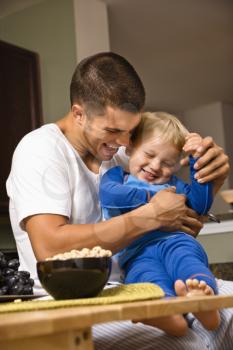 Royalty Free Photo of a Father Tickling His Toddler Son in the Kitchen