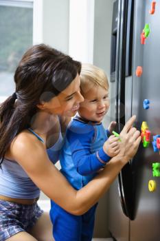 Royalty Free Photo of a Toddler and Mother Playing With Magnets on a Refrigerator
