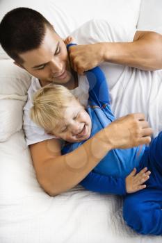 Royalty Free Photo of a Toddler Boy and Father Playing in Bed
