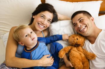Royalty Free Photo of a Family Laying in Bed Smiling