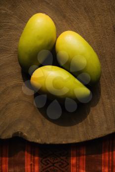 Royalty Free Photo of a Still Life of Three Wooden Mangoes on a Plate