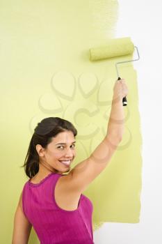 Royalty Free Photo of a Woman Painting the Interior Wall of Home with a Paint Roller