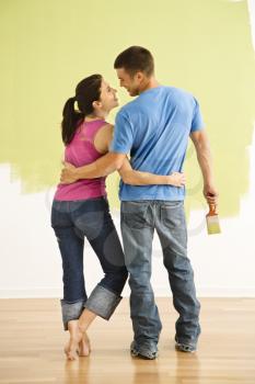 Royalty Free Photo of a Couple Standing in Front of a Partially Painted Wall With Arms Around Each Other