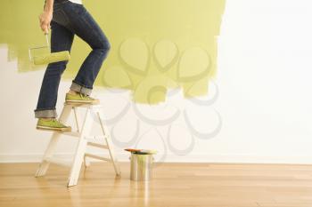 Royalty Free Photo of a Woman's Legs Climbing a Stepladder Holding a Paint Roller