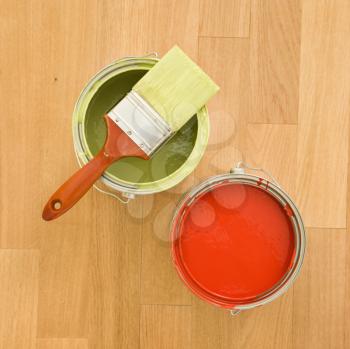 Royalty Free Photo of a Paintbrush With Paint Cans on a Wood Floor