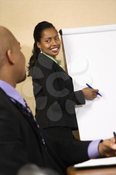Royalty Free Photo of Businesspeople Sitting at a Conference Table While a Businesswoman Gives a Presentation