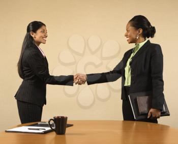 Royalty Free Photo of Two Businesswomen in Suits Shaking Hands and Smiling