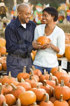 Royalty Free Photo of a Couple Picking Out Pumpkins and Smiling at an Outdoor Market