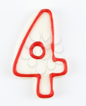 Sugar cookie in the shape of a number four outlined in red icing.