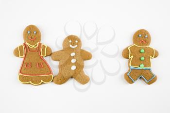 Frowning male gingerbread cookie standing separate from happy gingerbread cookies holding hands.