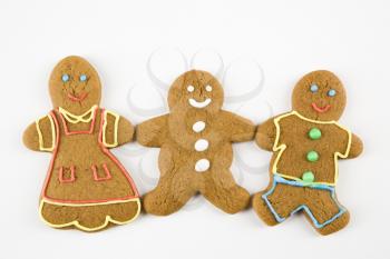 Three male and female gingerbread cookies holding hands.
