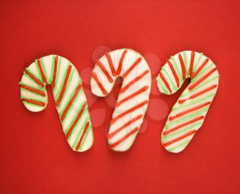 Three candy cane sugar cookies with decorative icing.