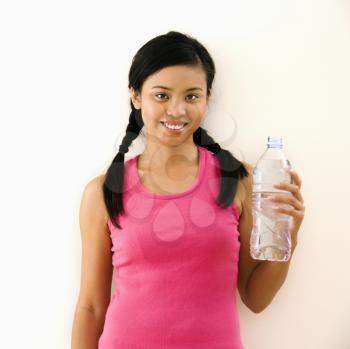 Royalty Free Photo of a Woman in a Fitness Outfit Holding Bottled Water and Smiling