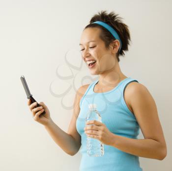 Royalty Free Photo of a Woman in Fitness Clothing Holding Bottled Water and a Cellphone